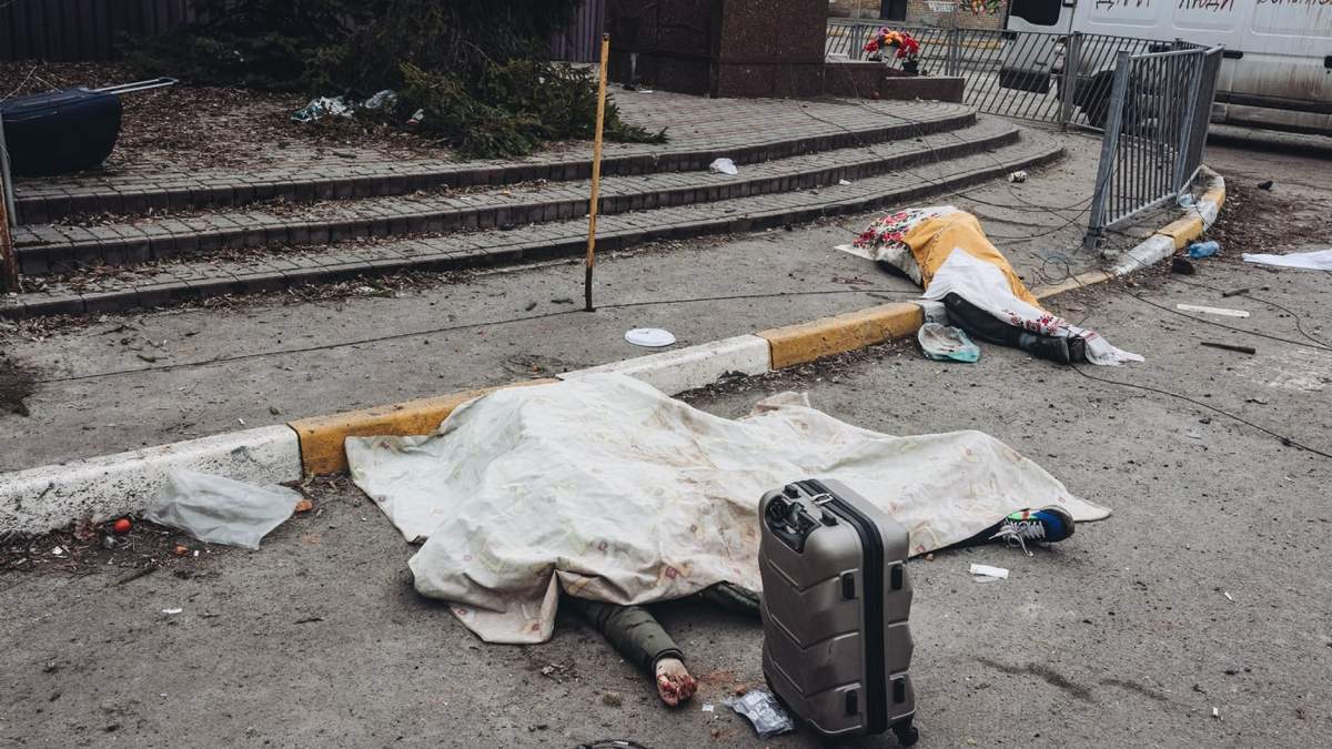 Un voluntario y una persona yacen en el suelo después del bombardeo del ejército ruso en el punto de evacuación de Irpin, Ucrania