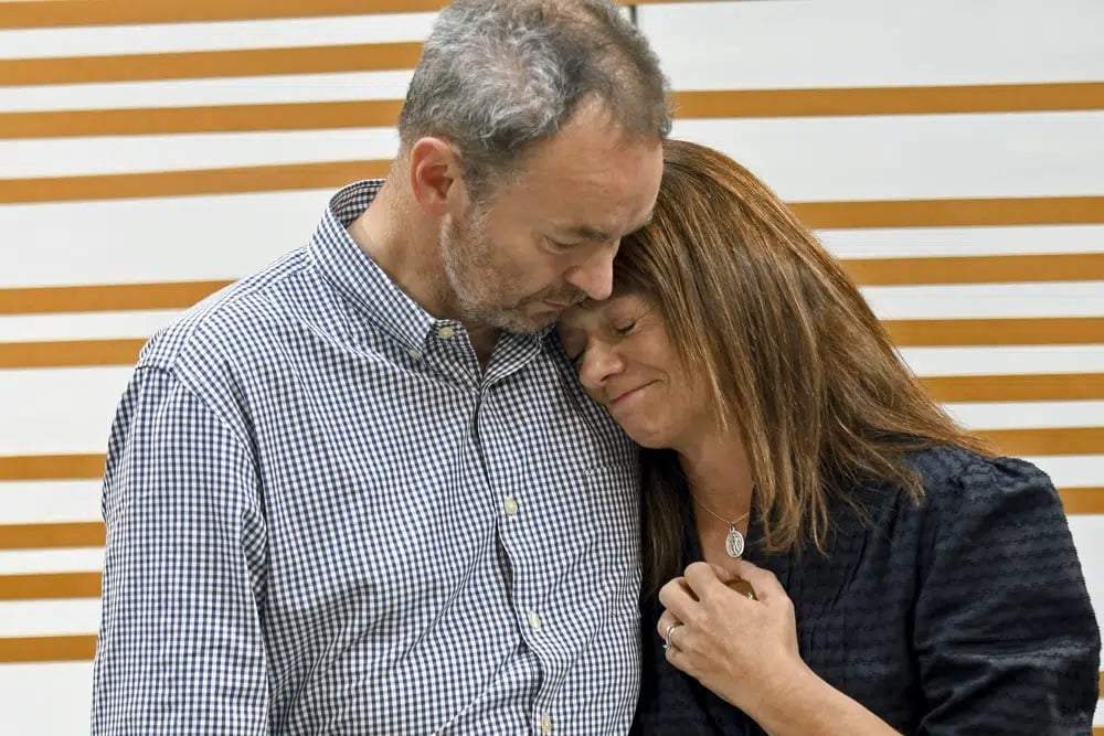 Simon y Sally Glass, padres de un joven que murió a tiros por policías cuando tuvo un episodio de salud mental, se consuelan en un momento de emoción durante una conferencia de prensa en Denver