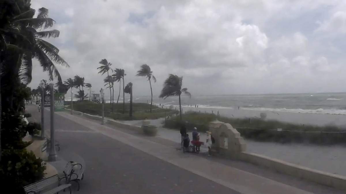Gente camina por una playa mientras la tormenta tropical Debby avanza por el Golfo de México hacia Florida