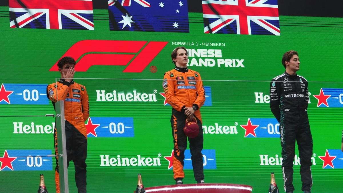 El australiano Oscar Piastri de McLaren celebra el primer lugar en el podio al lado de su compañero de equipo, el británico Lando Norris y George Russell de Mercedes