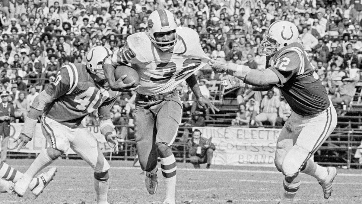 O. J. Simpson, corredor de los Bills de Buffalo, trata de avanzar mientras es tirado del jersey por Mike Curtis, linebacker de los Colts de Baltimore, en un partido del 12 de octubre de 1975