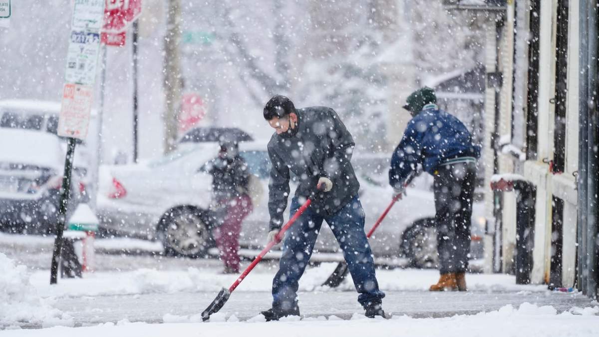 Personas limpian una acera durante una tormenta de nieve en Filadelfia, el 13 de febrero de 2024