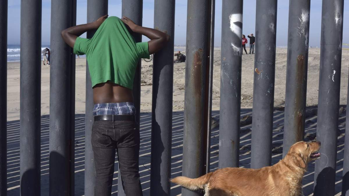 Migrantes centroamericanos en el muro fronterizo en Baja California