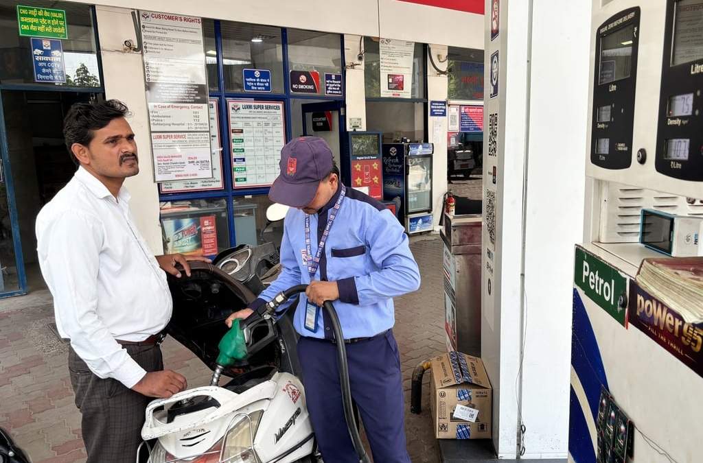 Un conductor controla el precio del combustible mientras un trabajador llena el depósito de su moto en una gasolinera en Nueva Delhi, India