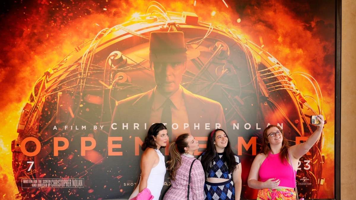 Fans de Barbie se toman una selfie frente al cartel de Oppenheimer