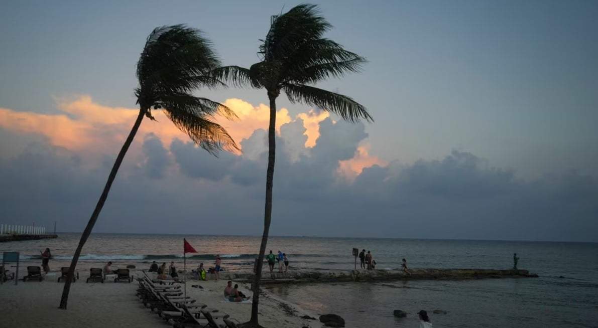 Gente en la playa mientras se pone el sol antes de la llegada del huracán Beryl en Playa del Carmen