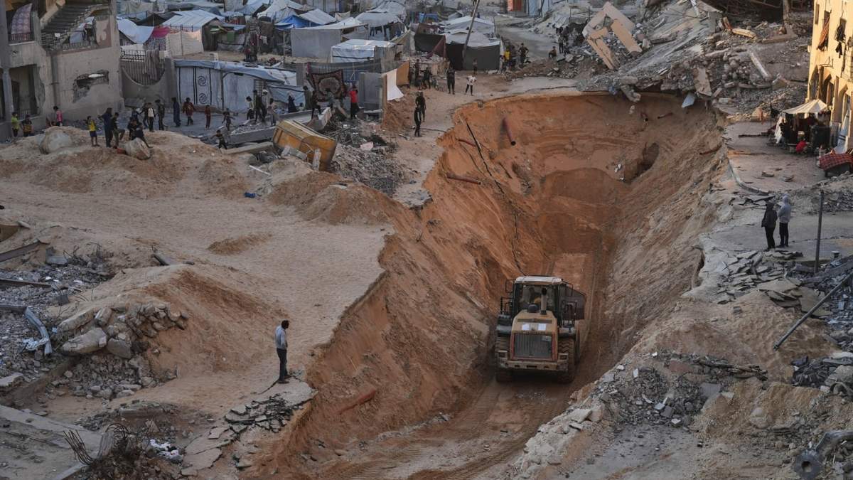 Palestinos miran a miembros del grupo armado Hamás buscar cuerpos en Jan Yunis, en el sur de la Franja de Gaza