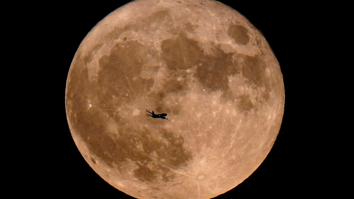 Un avión pasa frente a una superluna, el 13 de julio de 2022, en Milwaukee