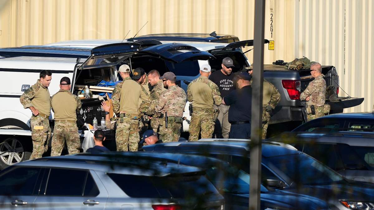 Agentes se reúnen en el estacionamiento de una escuela en la búsqueda de Robert Card, un reservista del ejército al que las autoridades acusan de matar a tiros a 18 personas