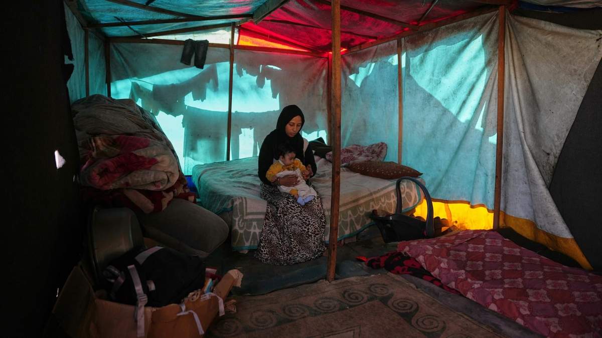 Shaimaa Wadi, de 25 años, con su hija de 1 año, Tala, dentro de su tienda en un campamento improvisado para palestinos desplazados en Deir al-Balah