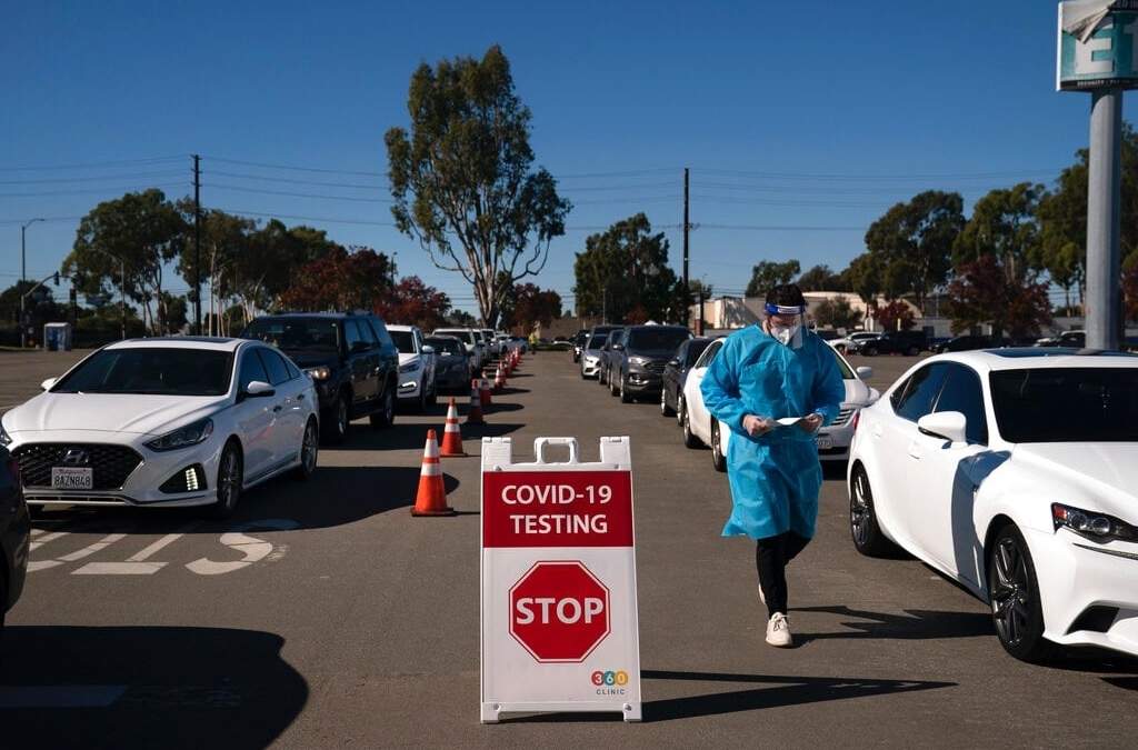 El estudiante de enfermería Ryan Eachus recolecta formularios mientras los autos se alinean para las pruebas de covid-19