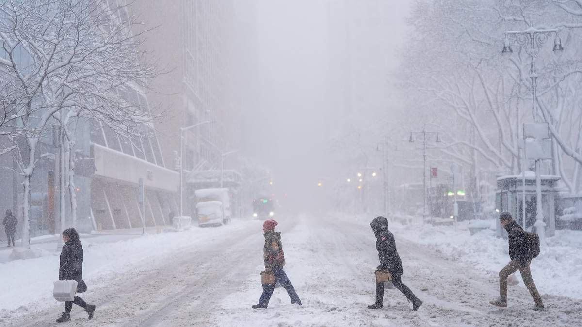 Peatones cruzan la calle 42 cerca de Bryant Park durante una tormenta de nieve el lunes
