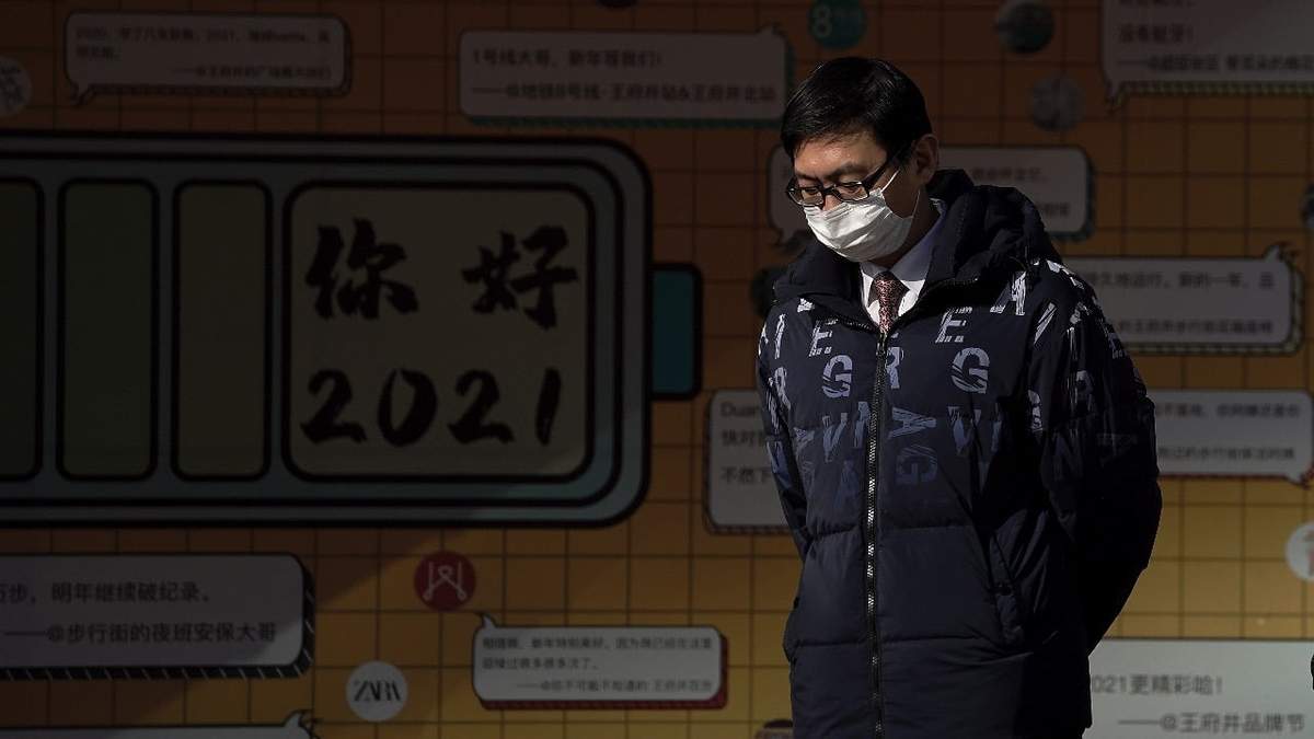 Un hombre camina en Beijing con cubrebocas