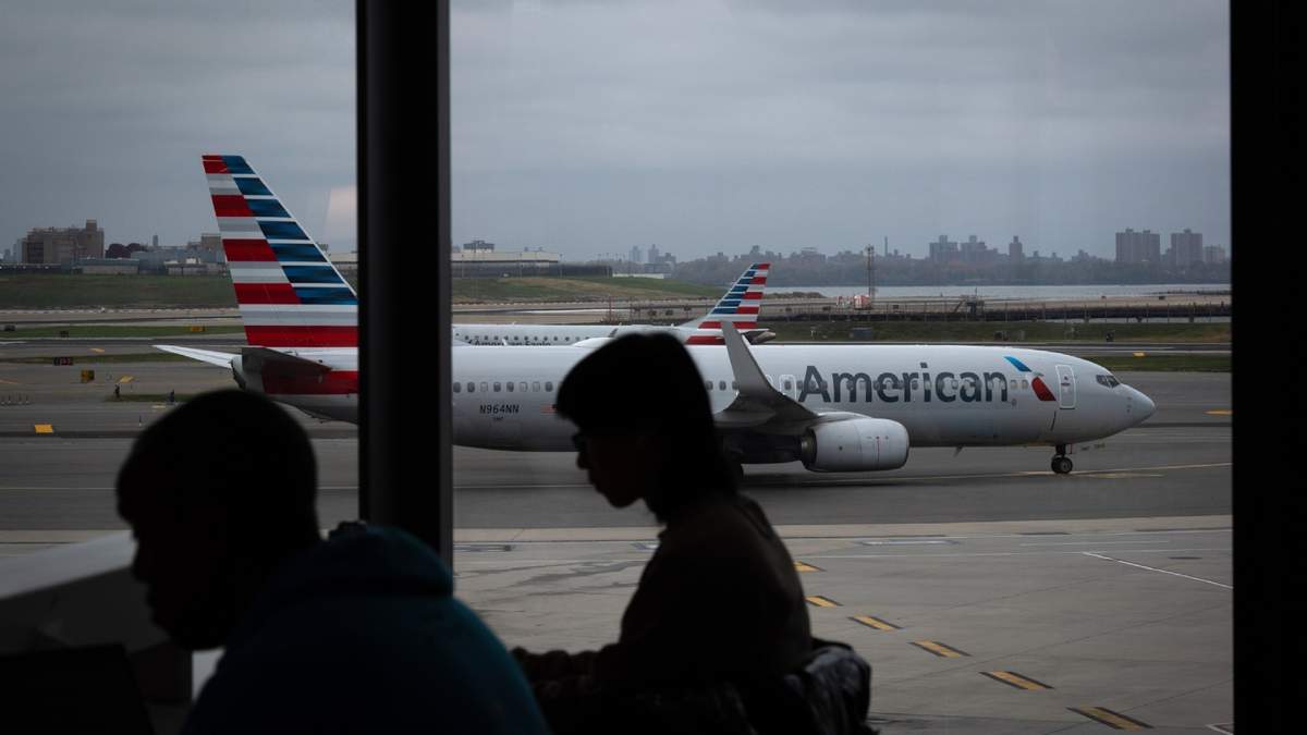 Gente esperando a vuelos mientras un avión de American Airlines circula por la pista en el aeropuerto LaGuardia (LGA) en el barrio de Queens, Nueva York