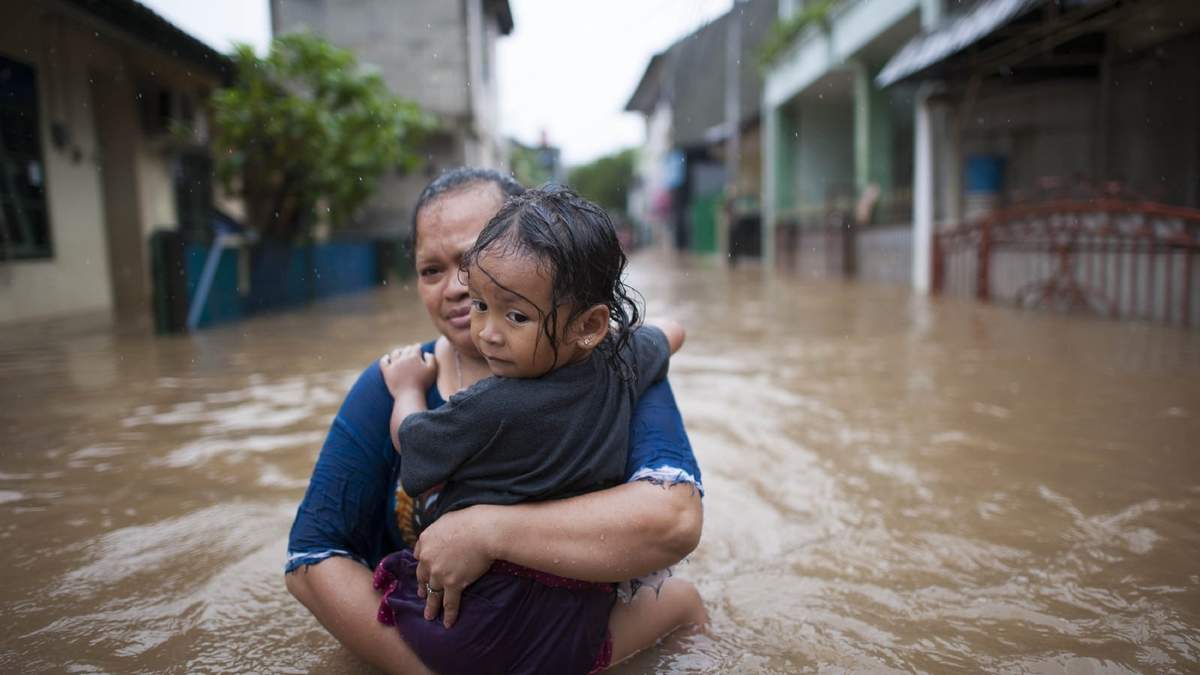 Una madre sostiene a su hijo en medio de las inundaciones de Sumatra, Indonesia. Fuente: (Twitter)