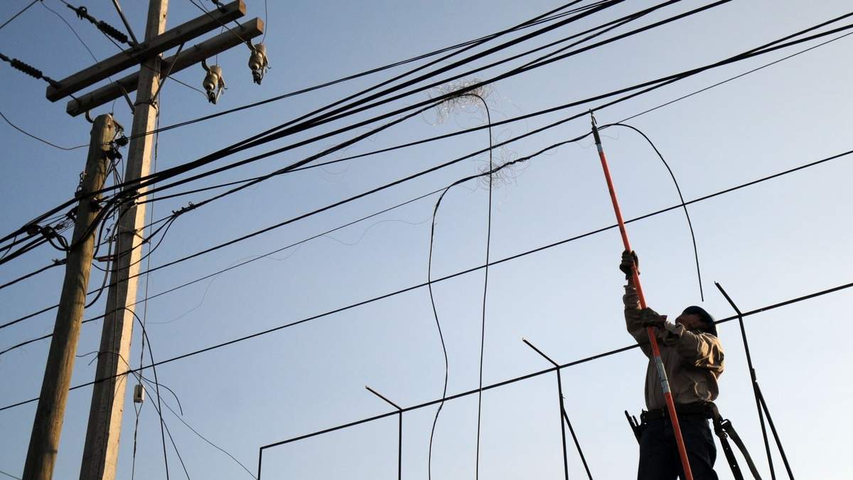 Un trabajador hace reparaciones en el cableado de un poste