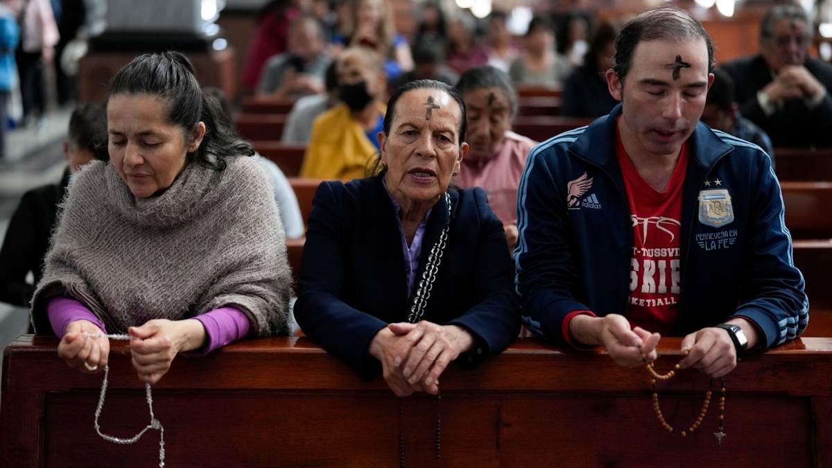 Católicos rezan el rosario al tiempo que un sacerdote marca la frente de los fieles con ceniza durante la misa del Miércoles de Ceniza en la Iglesia del Divino Niño en Bogotá, Colombia