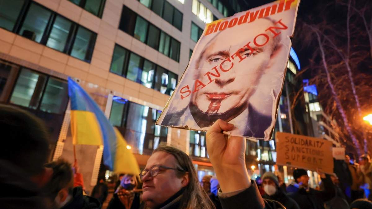 Un manifestante de Ucrania pide sanciones frente a la policía durante una manifestación afuera de una cumbre extraordinaria de líderes de la UE sobre Ucrania, en Bruselas