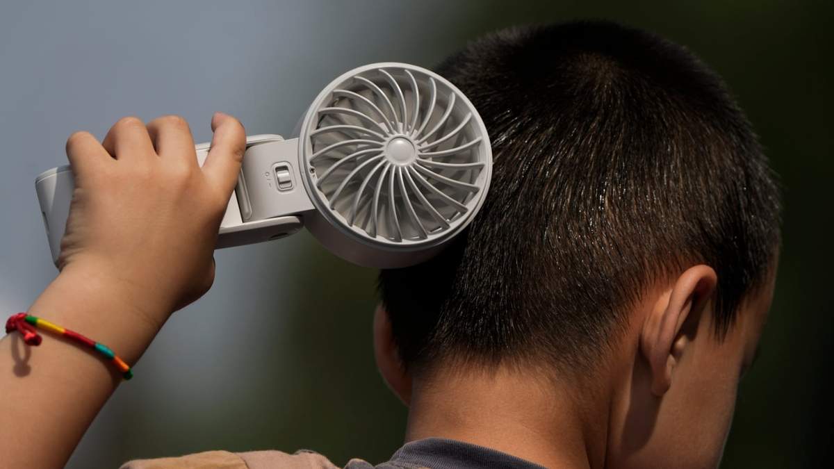 Un niño se refresca con un ventilador eléctrico en un día sofocante en un parque de Tongzhou, en las afueras de Beijing