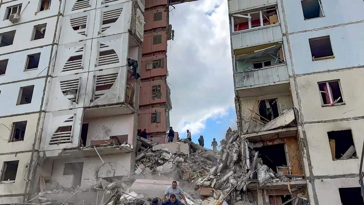 En esta imagen tomada de un video publicado por el canal de Telegram del gobernador regional de Belgorod, Vyacheslav Gladkov, el domingo 12 de mayo de 2024, los servicios de emergencia rusos trabajan en un edificio residencial parcialmente derruido durante un ataque de proyectiles ucranianos, en Belgorod, Rusia