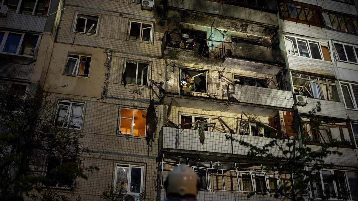 Trabajadores de emergencia guían a sus colegas en un edificio residencial dañado tras un ataque ruso en Kiev, Ucrania