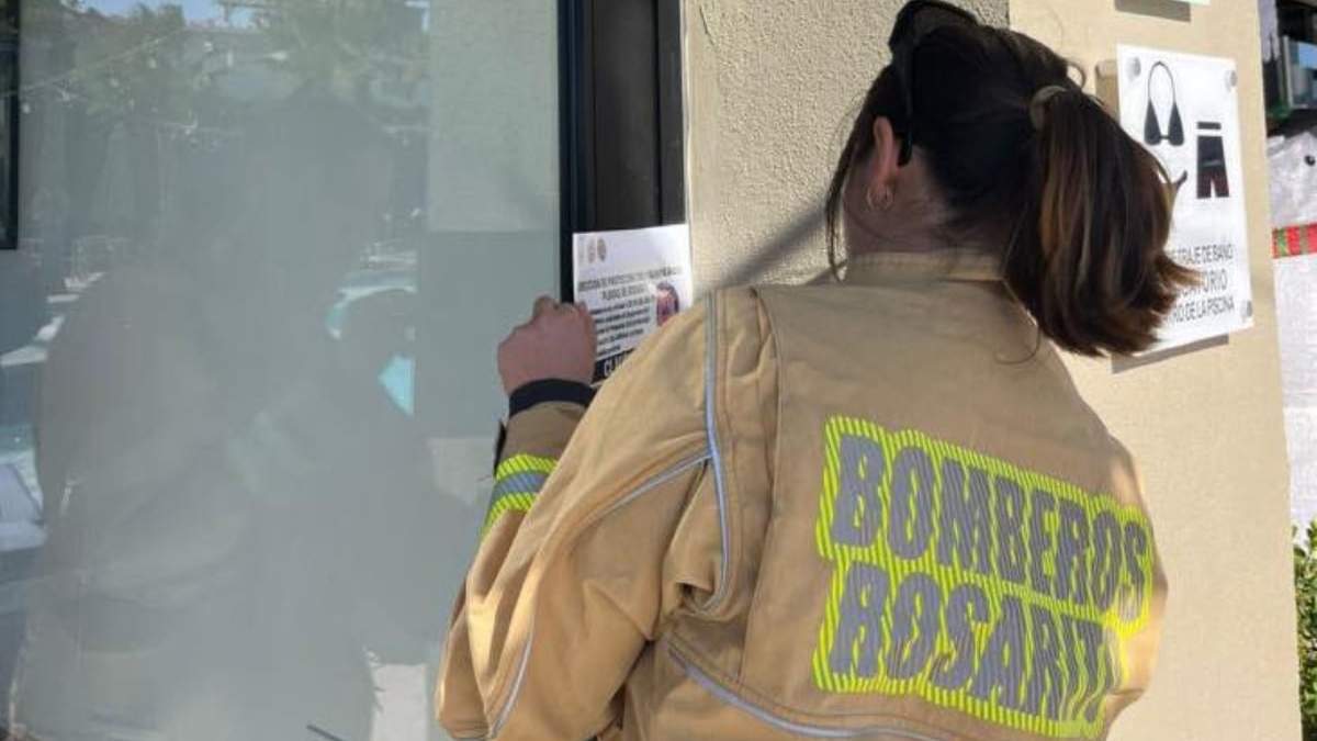 Una integrante del cuerpo de Bomberos coloca un sello de clausura en las instalaciones