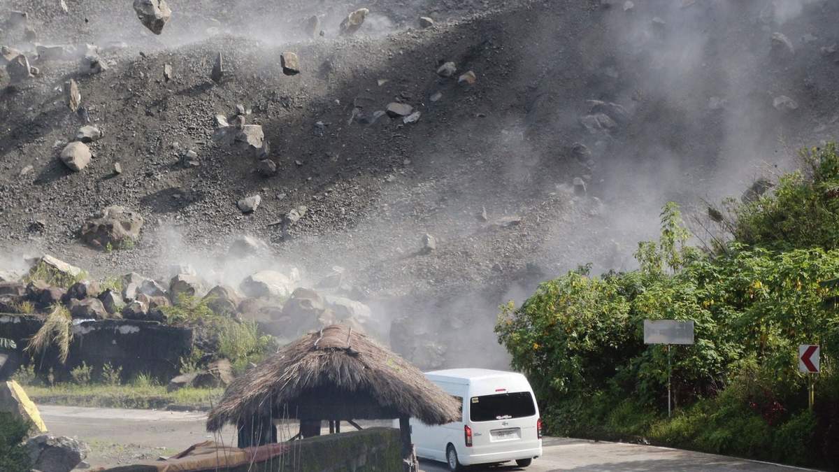 Rocas caen por una ladera mientras un vehículo circula por una carretera durante un sismo en Bauko, en la provincia de La Montaña, Filipinas