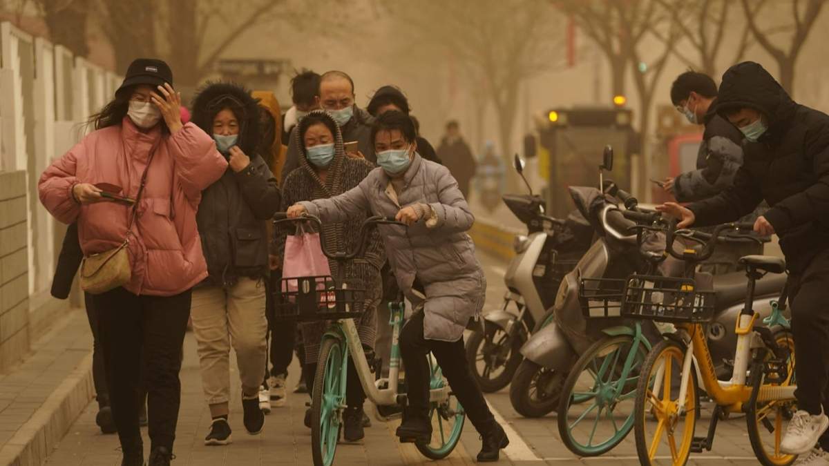 Las personas transitan en China en medio de la tormenta de arena. Fuente: (Twitter)