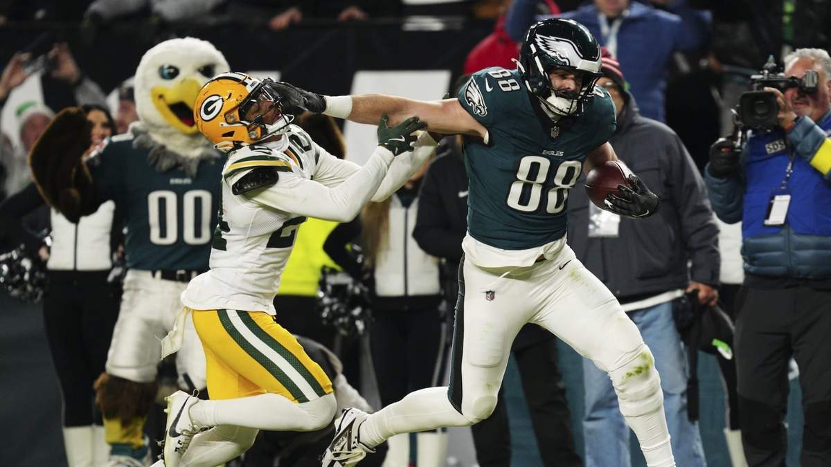 Dallas Goedert de Filadelfia aplica un stiff arm a Carrington Valentine de Green Bay