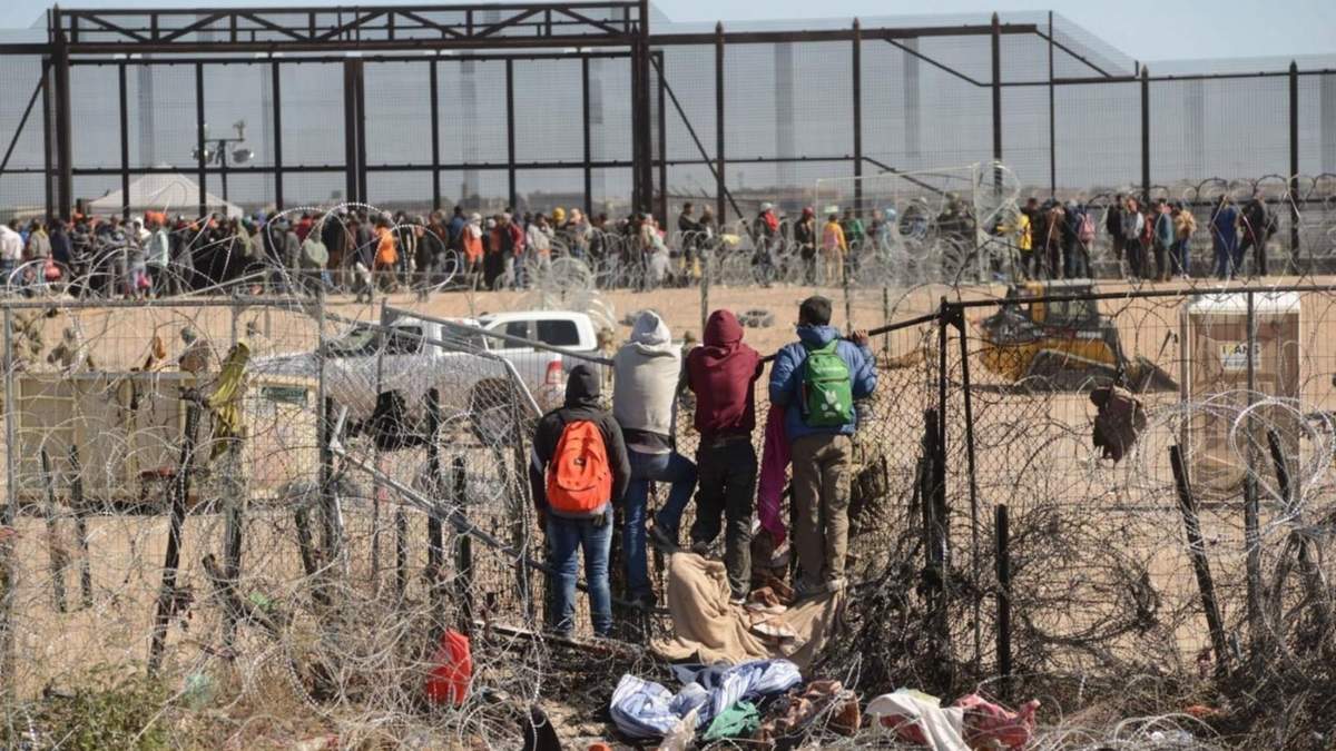 Migrantes cruzan y brincan la malla de alambre de púas en la puerta 36 de la frontera entre México y los Estados Unidos