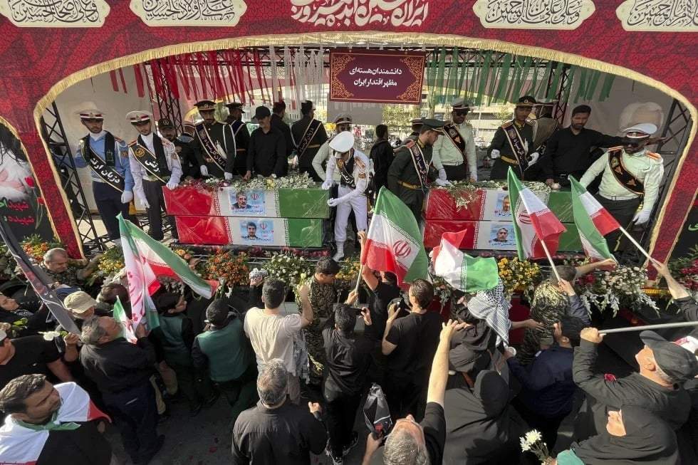 Un grupo de personas despiden los féretros, envueltos en banderas iraníes, de los científicos nucleares fallecidos en ataques israelíes, durante su funeral en Teherán. Irán, el 28 de junio de 2025.