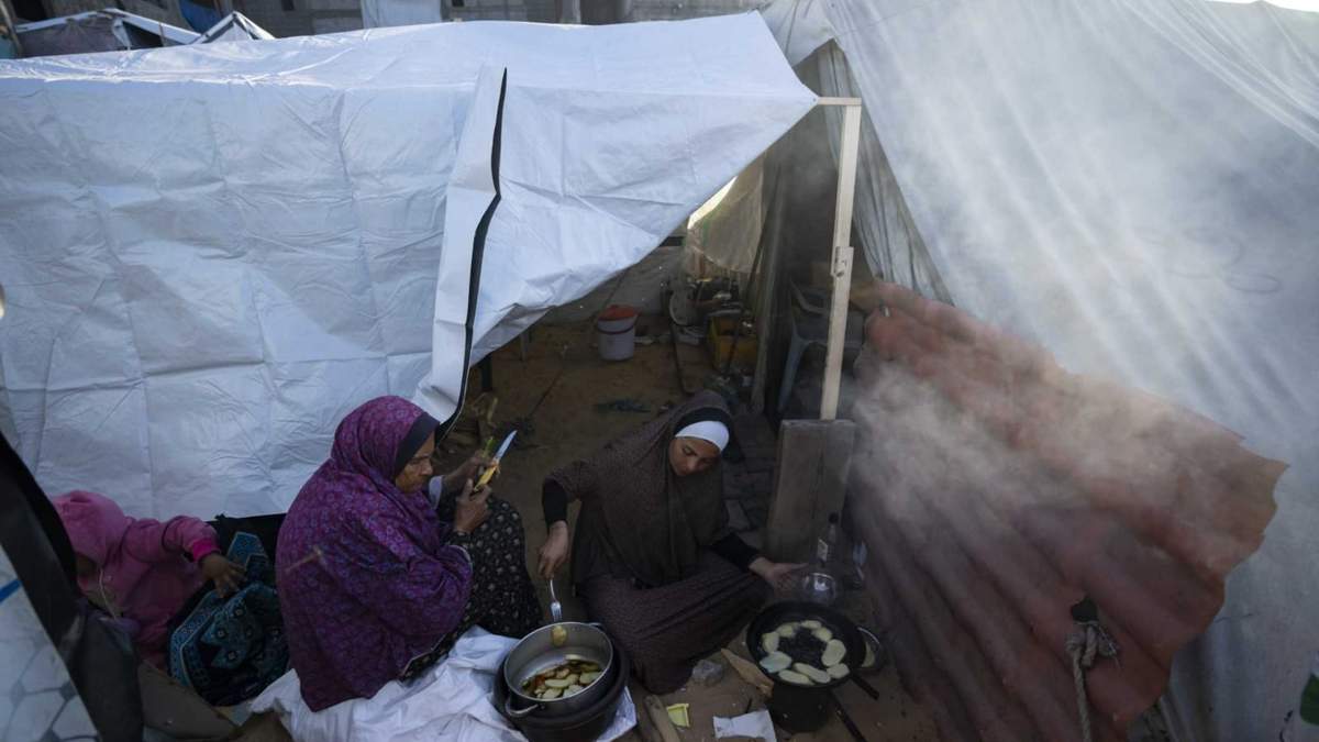 ARCHIVO - Randa Baker, a la derecha, desplazada por el bombardeo israelí de la Franja de Gaza, prepara la comida del iftar con su madre en el primer día del mes feriado musulmán del Ramadán, en un campamento improvisado en la zona de Muwasi, en el sur de Gaza, el 11 de marzo de 2024.. El ejército israelí ordenó el 22 de julio de 2024 la evacuación de parte de una zona de la Franja de Gaza que había designado como zona humanitaria