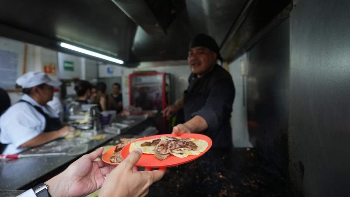 El chef Arturo Rivera Martínez, recién galardonado con una estrella Michelin, entrega una orden de tacos a un cliente en la taquería Tacos El Califa de León en Ciudad de México