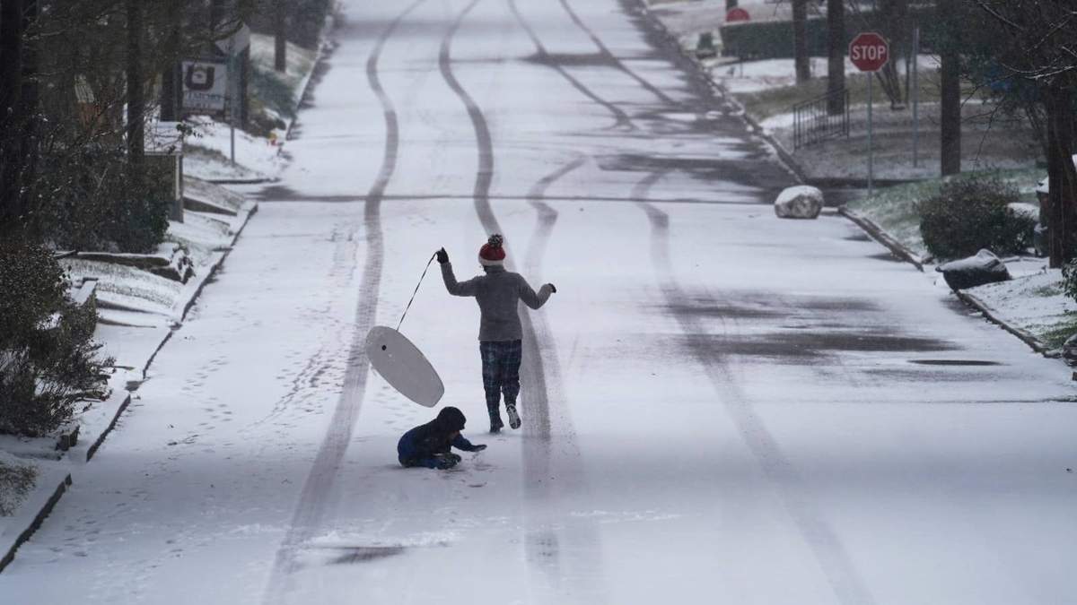 Niños juegan con un trineo en San Antonio, Texas, mientras la nieve sigue causando estragos en esa entidad