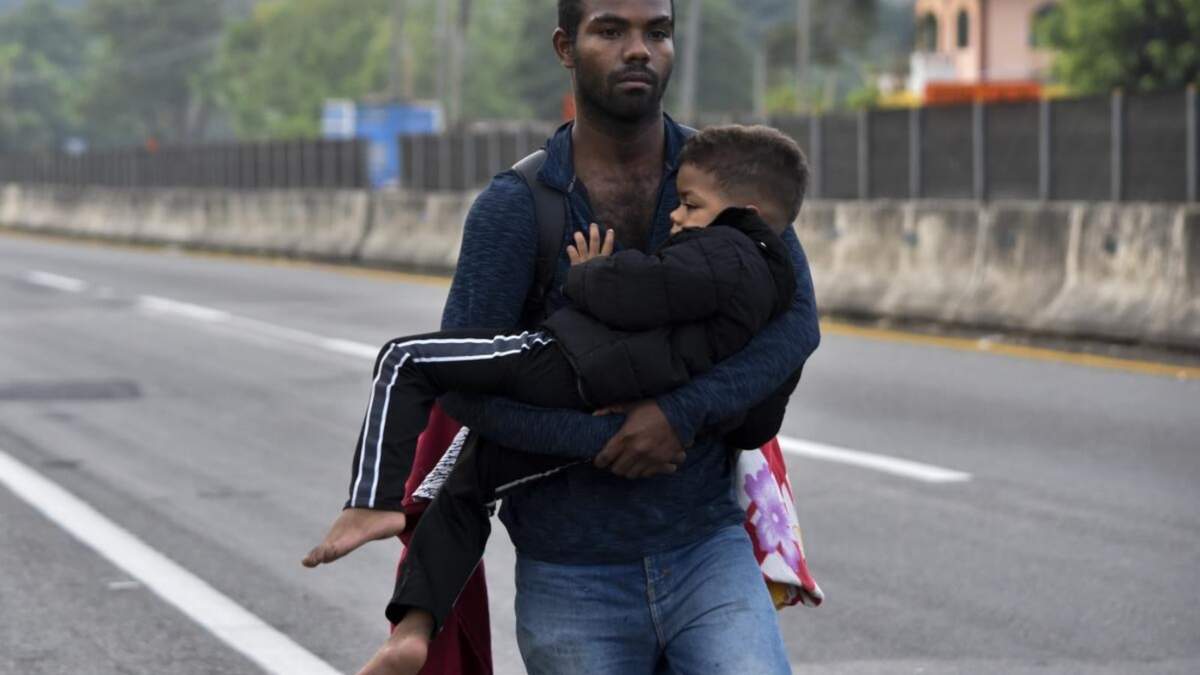 Un migrante carga a un niño por Tapachula, estado de Chiapas, México, como parte de una caravana de migrantes que intentan llegar a la frontera con Estados Unidos