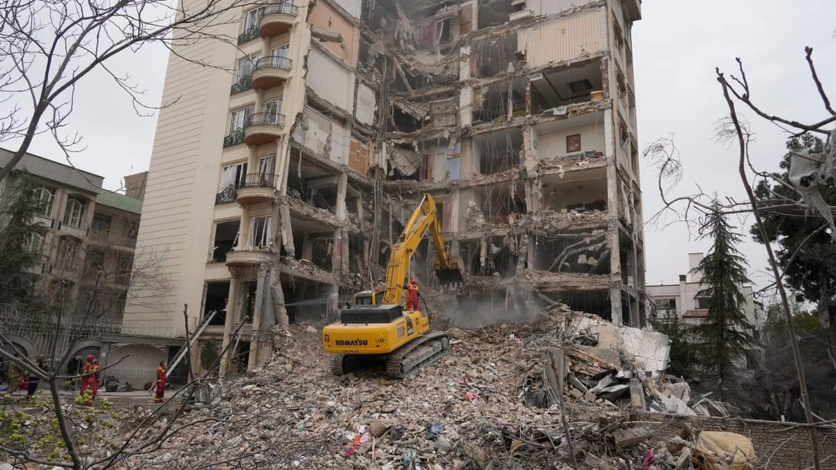 Bomberos iraníes usan una excavadora para retirar los escombros de un edificio residencial que recibió el impacto de un ataque de Estados Unidos e Israel, el lunes 23 de marzo de 2026, en Teherán, Irán