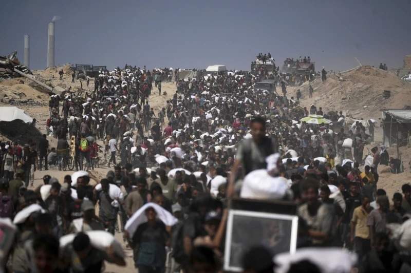 Palestinos cargan sacos de harina de un convoy de ayuda humanitaria rumbo a la ciudad de Gaza, en las afueras de Beit Lahiya, al norte de la Franja de Gaza, el viernes 1 de agosto de 2025.