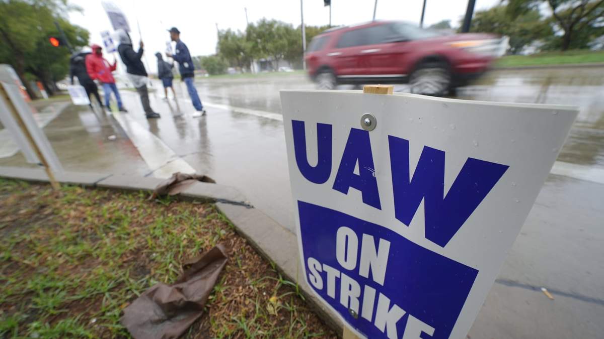 Automovilistas pasan junto a personas que protestan afuera de una planta de General Motors, en Arlington, Texas