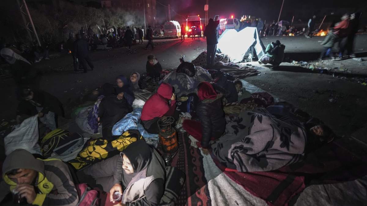 Palestinos desplazados se congregan con sus pertenencias cerca de un control de carretera en la carretera Rashid, mientras esperan para regresar a sus hogares en la zona norte de la Franja de Gaza