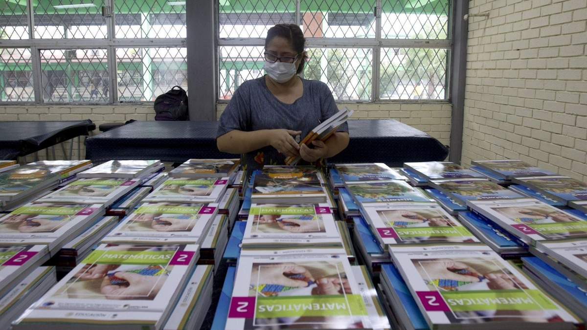 Una maestra organiza libros de texto para ser entregados a los padres de familia