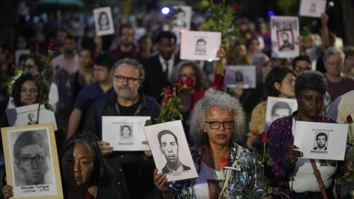 ARCHIVO - Manifestantes sostienen fotos de personas asesinadas en la dictadura de Brasil, durante la marcha "Caminata de silencio" en memoria de las víctimas, en el aniversario del golpe de Estado de 1964 en el país, en Sao Paulo