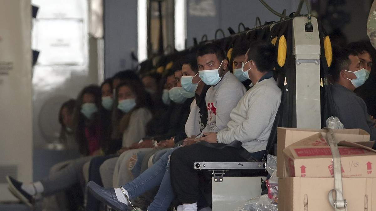 Migrantes con mascarillas y grilletes a la espera de ser deportados a Guatemala
