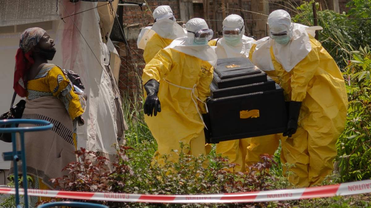 Una mujer llora mientras trabajadores de Cruz Roja cargan con el ataúd de una persona muerta por ébola en un centro de salud en Rwampara, República Democrática del Congo