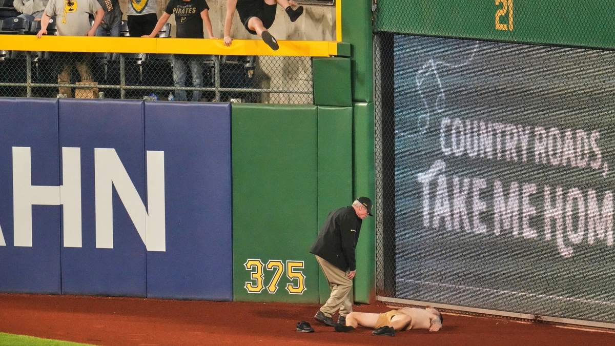 Un fanático yace en la fanja de advertencia del PNC Park, tras caer desde las gradas en el encuentro entre los Piratas de Pittsburgh y los Cachorros de Chicago