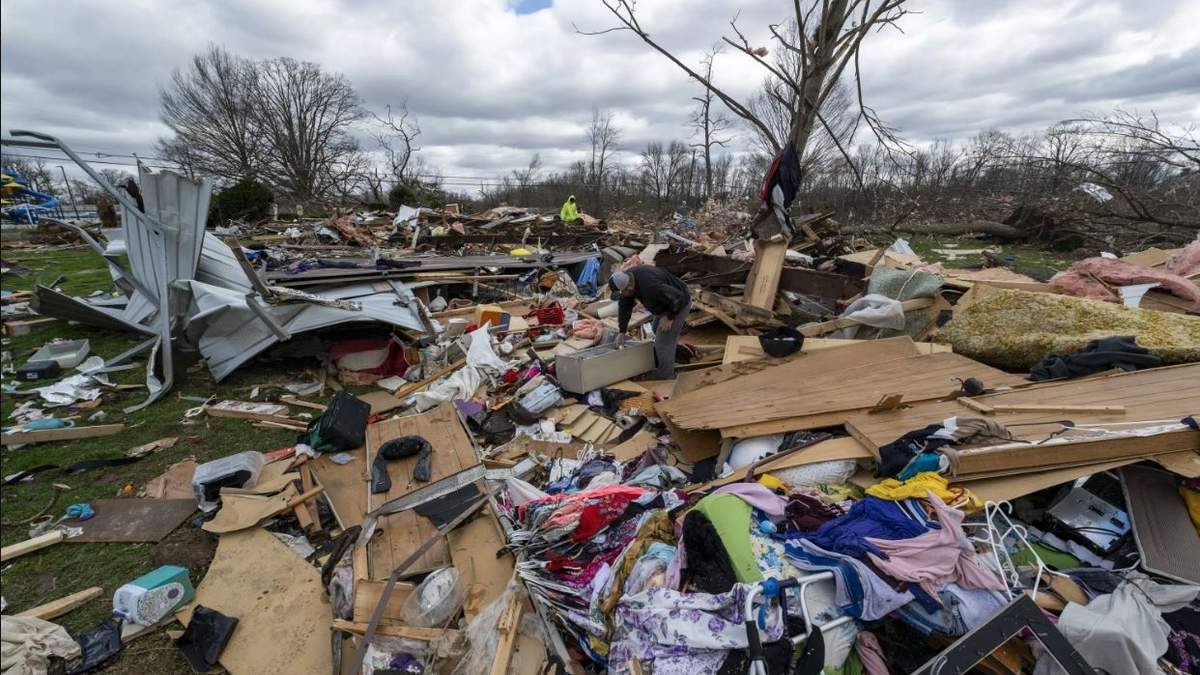 Gente entre los restos de un tornado nocturno en Sullivan, Indiana
