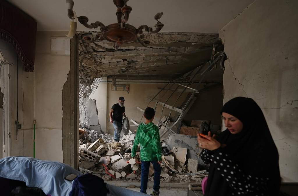 Fadi Al Zein, a la izquierda, que perdió sus dos casas en ataques israelíes en su pueblo de Khiam y en Dahiyeh, busca entre los escombros de su casa dañada con un niño cerca, en los suburbios sureños de Beirut, Líbano, el sábado 25 de abril de 2026