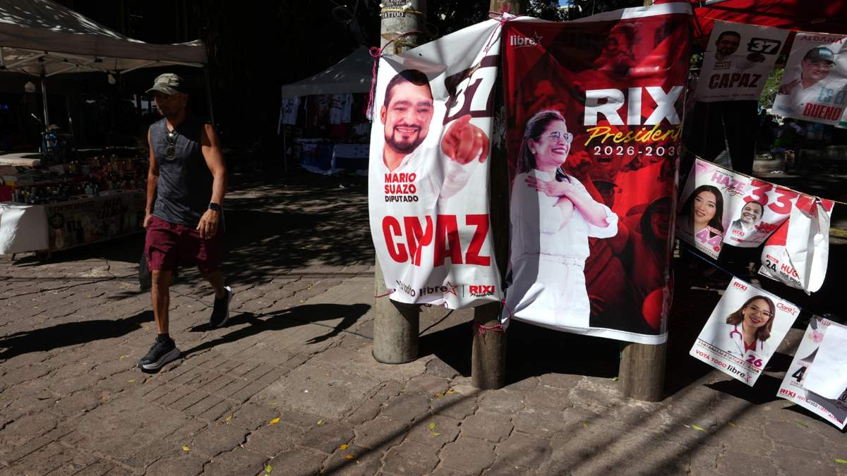 Un hombre pasa junto a un puesto con carteles de campaña de la candidata presidencial del partido gobernante, Rixi Moncada, en Tegucigalpa, Honduras