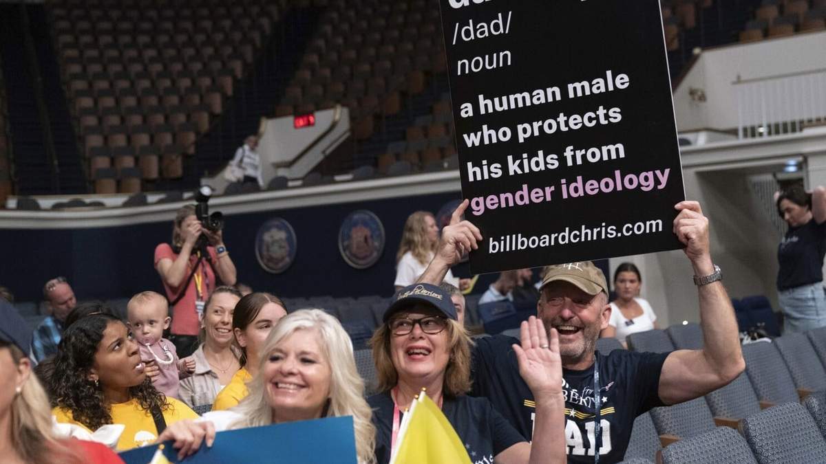 Un grupo de participantes sostienen sus carteles en la cumbre nacional de Moms for Liberty en Washington