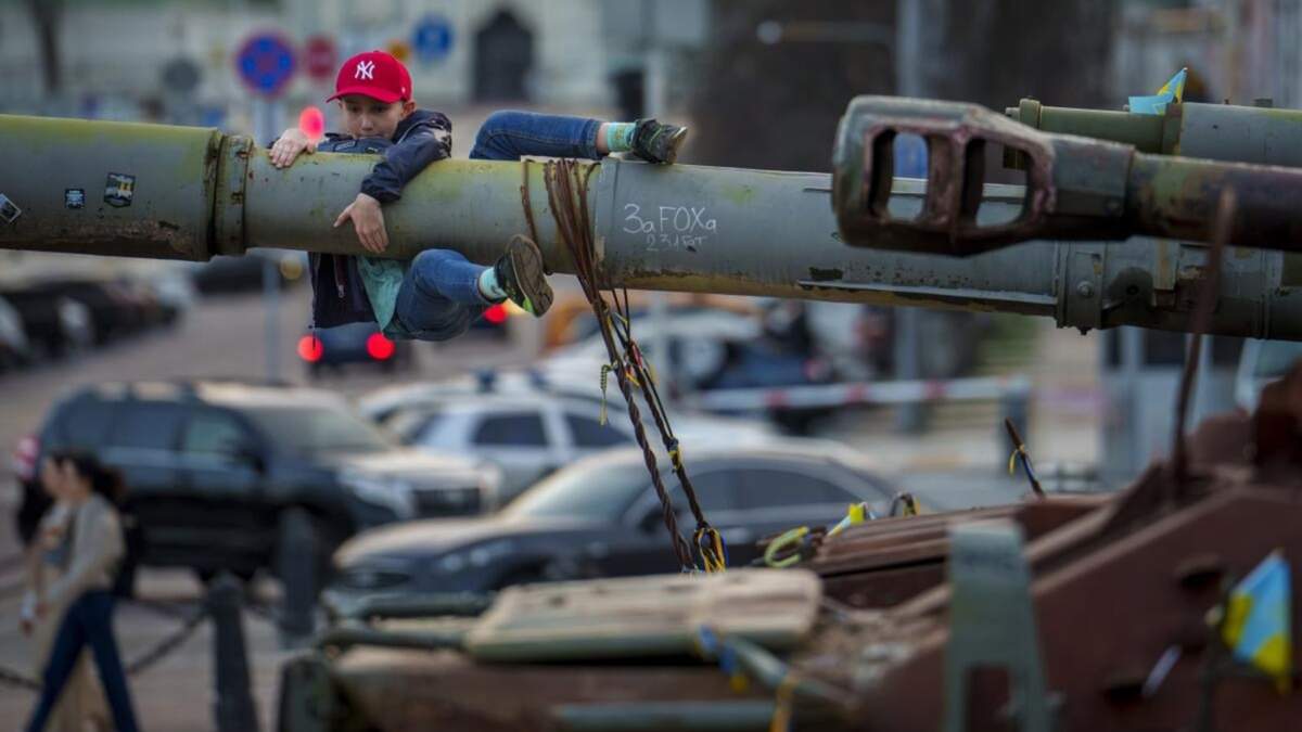 Un niño se cuelga del cañón de un tanque expuesto junto con otro equipamiento militar ruso destruido, en Kiev, Ucrania