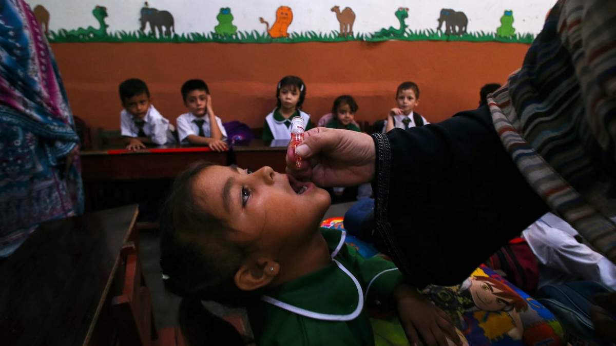 Una trabajadora sanitaria administra una vacuna contra la polio a un menor en una escuela de Peshawar, Pakistán